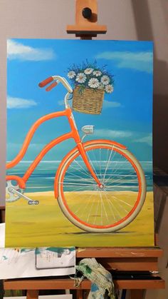 an orange bicycle with flowers in the basket is sitting on a easel next to a painting