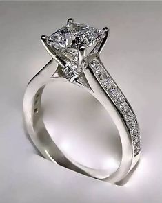 a white gold engagement ring with princess cut diamonds on the side and channeled band