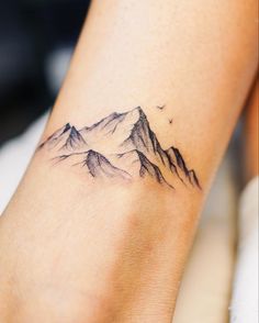 a woman's foot with a small mountain tattoo on the left side of her leg