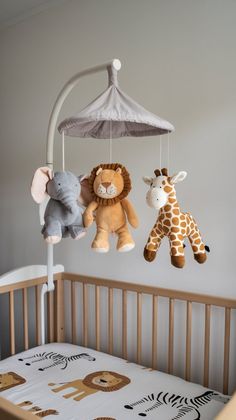 three stuffed animals hanging from a mobile in a baby's crib