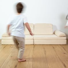 two children are playing on the floor in front of a white couch and wooden floors