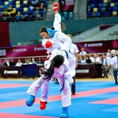 two women in white and blue uniforms are doing tricks on the floor while people watch