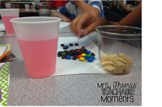 a table with two cups and some candy on it, one pink cup is filled with gummy bears