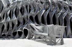 an artistic sculpture is shown in front of a building that has been made out of metal sheets