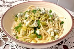 a bowl filled with pasta and vegetables on top of a lace doily covered table