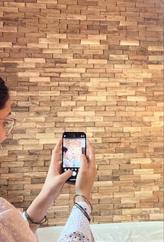 a woman holding up her cell phone to take a selfie in front of a wooden wall