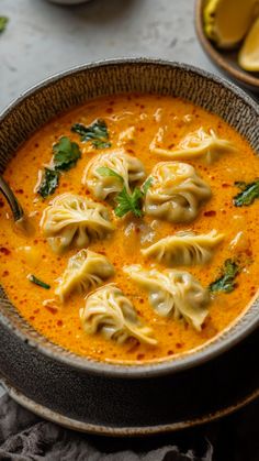 a bowl filled with dumplings and sauce on top of a table