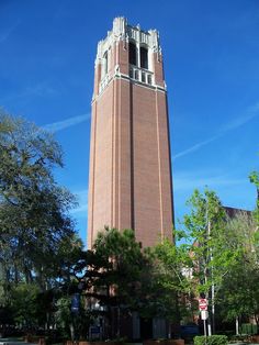 a tall brick tower with a clock on it's side in the middle of a park