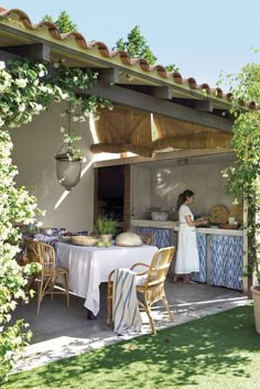 a woman standing in front of a table with food on it under an awning