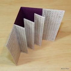 three pieces of folded paper sitting on top of a wooden table