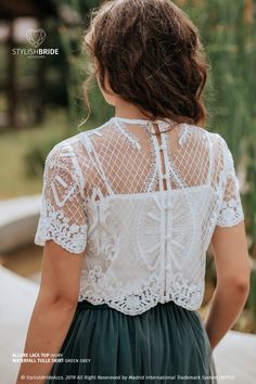 the back of a woman's white top with lace detailing and green pleated skirt