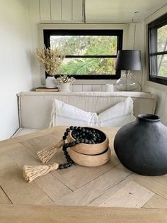 a table topped with a bowl filled with blueberries next to a black vase on top of a wooden table