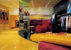 a brightly colored clothing store with yellow flooring and red furniture in the center,