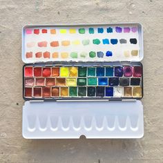 the watercolor palettes are sitting on top of each other in an empty container