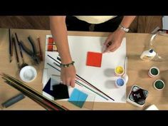 a woman is working on an art project with paints and pencils in front of her