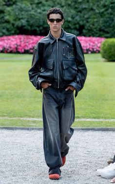 a man in black leather jacket and pants walking