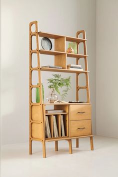 a wooden shelf with books and magazines on it, next to a plant in a vase