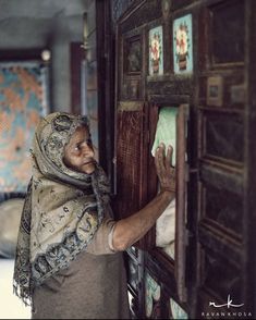 an old man is looking at pictures on the wall in front of his home door