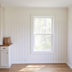 an empty room with white walls and wood floors