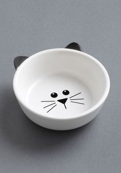 a white bowl with a black cat's face painted on the front and side