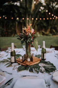 the table is set with wine bottles and flowers