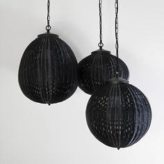 two black lamps hanging from chains on a wall