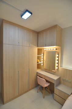 a bedroom with a vanity, mirror and stool next to the closet doors that have lights on them