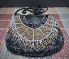 "This designer Nina Ricci (Paris) evening bag is so beautiful and luxurious. A lot of work went into this purse.  It is a beautiful work of art and well preserved.  The bead work is outstanding with black, bronze and gold beads and fringe dangles. The bag is lined with black satin and its roomy interior has one side slip pocket. The purse has a zip top closure and has a long and twisted satin cord. This lovely bag measures about 6 ½\" tall, 6 1/2\" across the top and 7 1/2\" toward the bottom. T Elegant Handmade Evening Shoulder Bag, Elegant Evening Handmade Shoulder Bag, Traditional Beaded Evening Shoulder Bag, Traditional Beaded Evening Bag For Events, Beaded Evening Shoulder Bag, Formal Beaded Shoulder Evening Bag, Gold Bohemian Evening Bag, Bohemian Handmade Shoulder Bag For Formal Occasions, Handmade Handheld Shoulder Bag For Celebrations