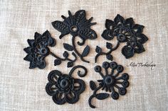 four black embroidered appliques with flowers and leaves on a white cloth fabric background