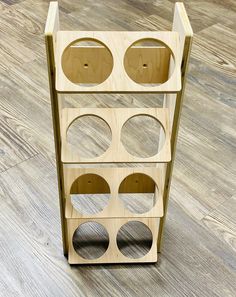 a wooden shelf with holes in it sitting on the floor next to a hard wood floor