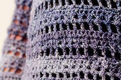 a close up view of a crocheted shawl with holes in the middle