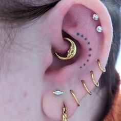 a person with ear piercings on their ears and behind the ear is a crescent