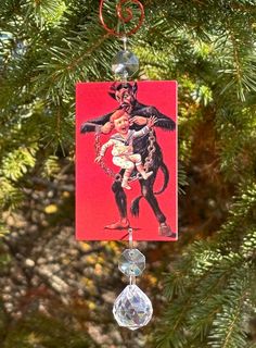 a christmas ornament hanging from a tree with an image of a monkey holding a baby