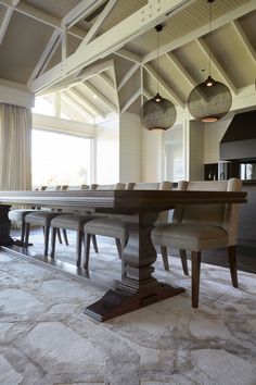 a dining room table with six chairs in front of an open floor plan and large windows