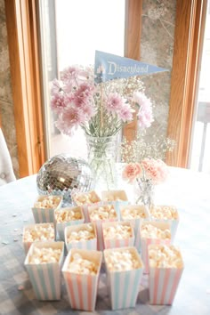 a table topped with lots of cupcakes next to a vase filled with flowers