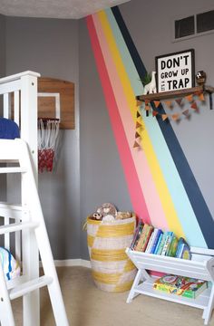 a child's bedroom with a rainbow painted wall and white bunk bed, ladder to the right