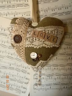 a heart shaped decoration hanging from a string on top of sheet music paper with the words love