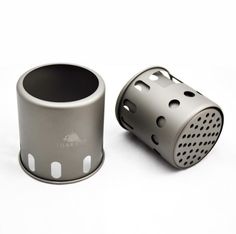 two stainless steel mugs sitting next to each other on a white surface with holes in them