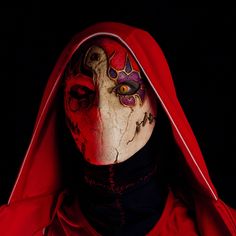 a person wearing a red hood and mask with blood on it's face, in the dark