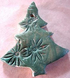 a green ceramic christmas tree ornament on a pink background