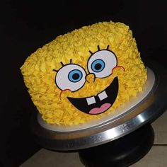 a spongebob cake with yellow frosting and blue eyes on a silver plate