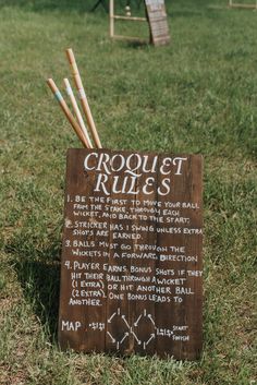 a wooden sign sitting on top of a grass covered field next to a park bench