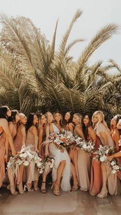 a group of women standing next to each other in front of palm trees and flowers