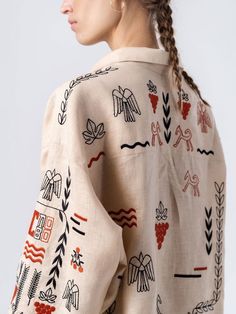 a woman with braids in her hair wearing a white shirt with red and black designs on it