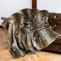 a brown leather couch sitting on top of a hard wood floor next to a wall