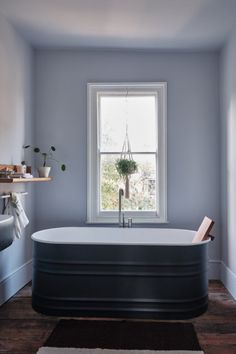 a bath tub sitting next to a window in a bathroom