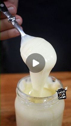 a person is spooning milk into a jar