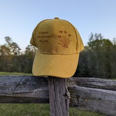 This wood burned yellow faux suede baseball cap would make a great addition to any nature lover's wardrobe. Using a woodburner and my own originial design I hand burnt dandelions on the right side of the crown of the hat. On the left side of the crown I burnt the quote "Wildflowers don't care where they grow". Materials: 100% cotton Hat fits 54cm-60cm with an adjustable buckle in the back making a it fit a wide range of sizes. *Disclaimer* colors may vary slightly from screen to screen Fedora Burning, Hat Cottagecore, Nature Birthday, Hat Burning, Hat Bar, Cottagecore Gifts, Unique Graduation Gifts, Hat Fits, Graduation Gifts For Her