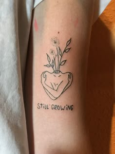 a tattoo on the arm that reads still growing with a flower in it's center