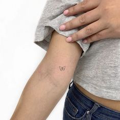 a woman's arm with a small butterfly tattoo on the left side of her right arm